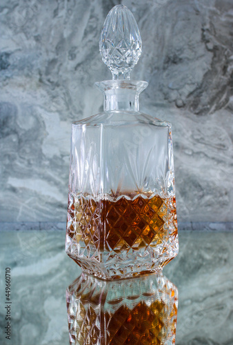 Crystal decanter with whiskey on a gray background