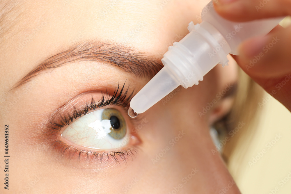 Young woman using eye drops on light background, closeup Young woman using eye drops on light background, closeup