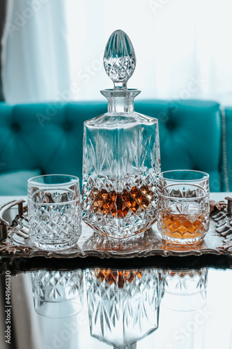 Glass decanter with alcohol and two glasses on a light background of the bar.