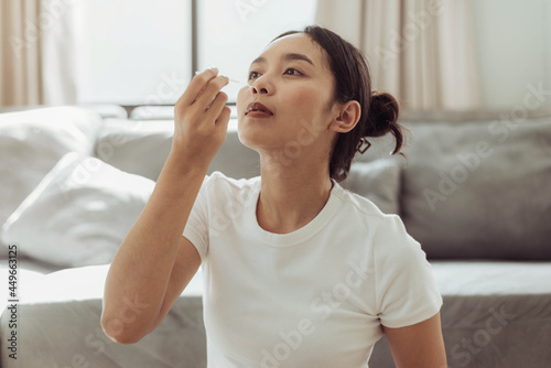 Young woman self test for COVID-19 at home with a nasal swab. asian woman using coronavirus covid-19 rapid antigen home testing kit, Coronavirus nasal swab test for infection. photo