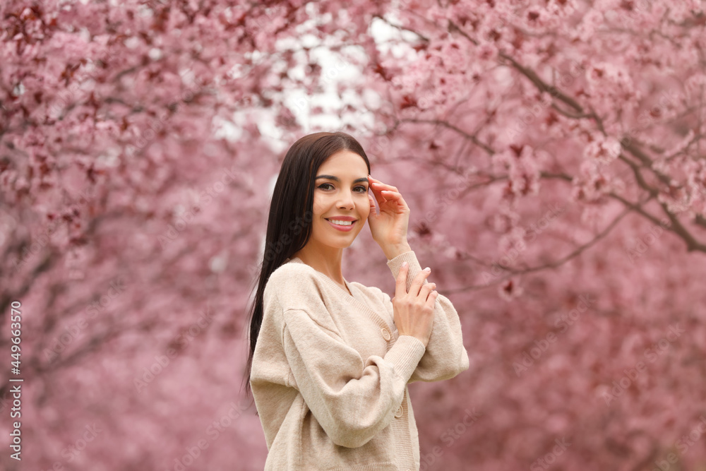 Pretty young woman in park with blooming trees. Spring look Pretty young woman in park with blooming trees. Spring look