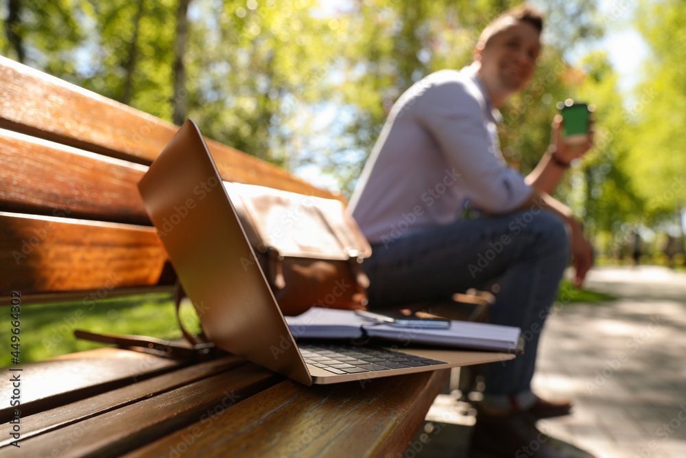 Man taking coffee break during work in park, focus on laptop Man taking coffee break during work in park, focus on laptop