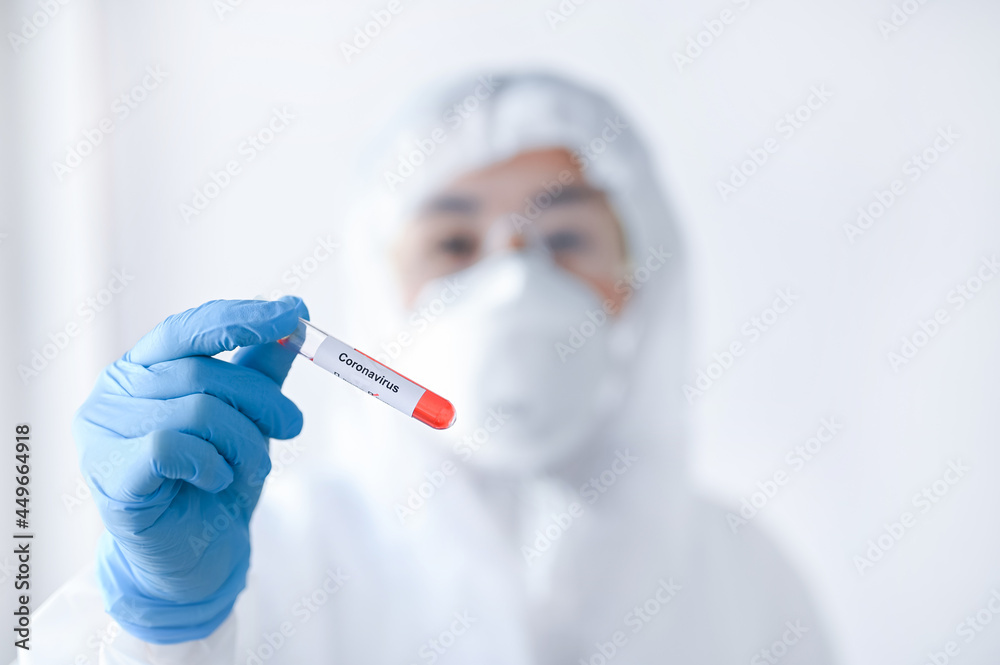 Selective focus of Corona virus blood sample in doctor hand in PPE suit. Selective focus of Corona virus blood sample in doctor hand in PPE suit.