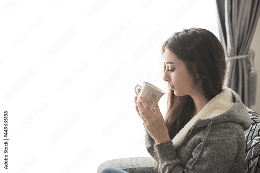 Attractive young woman with cup or coffee sitting on sofa at home. Attractive young woman with cup or coffee sitting on sofa at home.