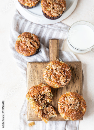 Freshly baked muffins with oat crumbs on wooden board with a cup of milk for healthy breakfast or snack.