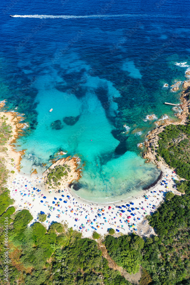 View from above, stunning panoramic view of a white sand beach full of beach umbrellas and people swimming in a turquoise water. Spiaggia del Principe,Sardinia, Italy.