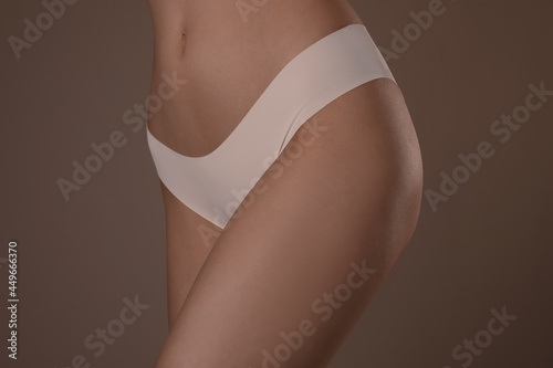 Slim woman with smooth skin in underwear on beige background, closeup. Cellulite problem concept