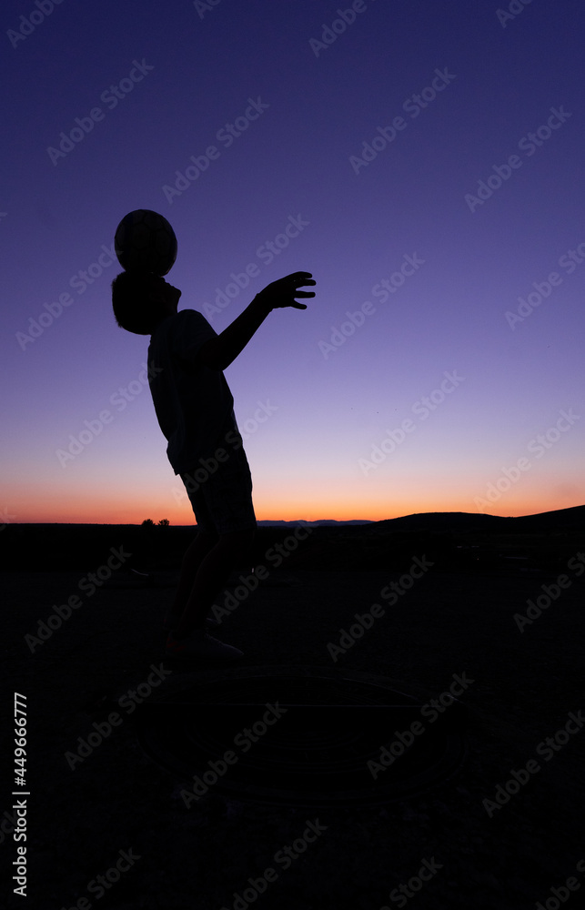 Fototapeta premium SILHOUETTE OF A BOY PLAYING BALL AT SUNSET