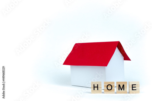 Home- word composed fromwooden blocks letters on red background, layout of a house with a red roof. copy space for ad text. photo