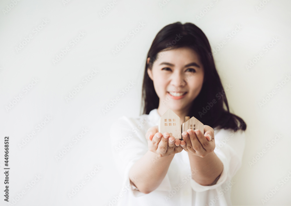 Selective focus of Wooden house and key on women hand. investment insurance and home purchase mortgage real estate concept.