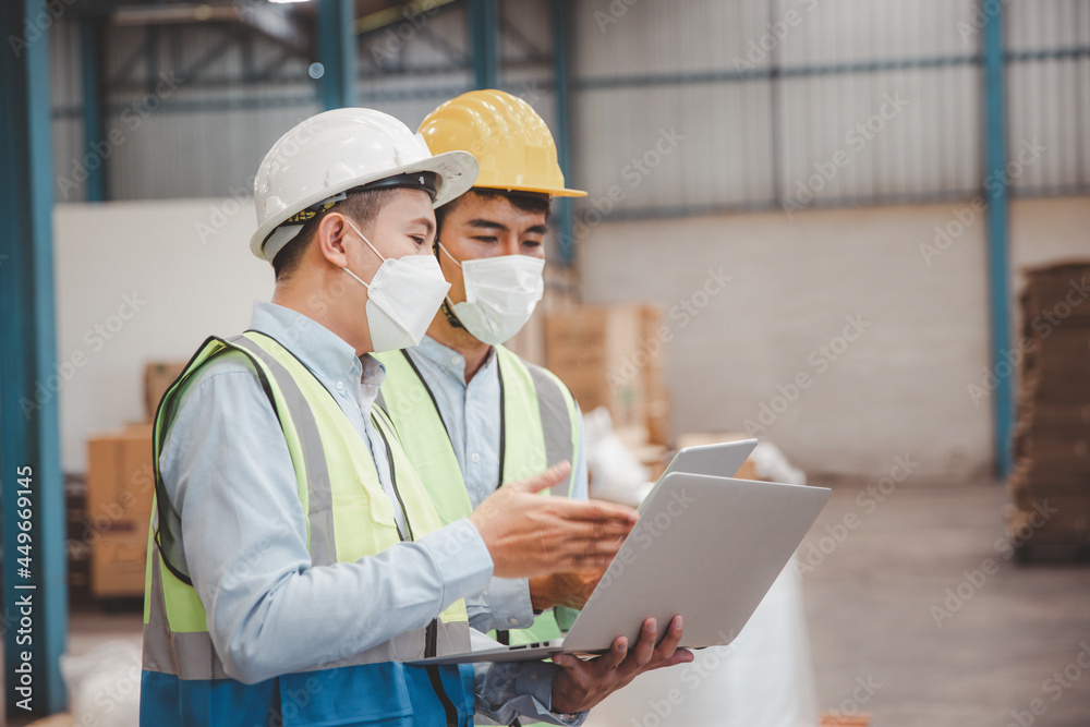 Factory manager and engineer in  medical mask and safety protective suite using computer laptop and digital tablet working discuss together