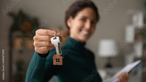 Close up focus on keys, smiling woman realtor selling apartment, offering to client, showing at camera, holding documents, contract, making purchasing deal, real estate agent, mortgage or rent photo