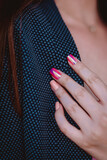 Female hand with pink manicure touching a blue jacket
