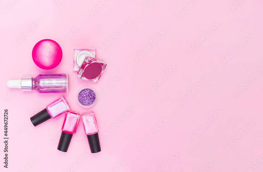 A set of cosmetics for manicure and pedicure on a pink and purple background. Gel varnishes, nail files, nail scissors, pusher, top view. Composition for a postcard with a place for the text