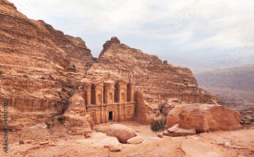 Ad Deir - Monastery - ruins carved in rocky wall at Petra Jordan, mountainous terrain with overcast sky background