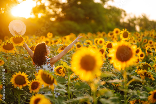 Beautiful woman strolling through field with sunflowers at sunset. Rural happy life. Nature, relax and lifestyle.