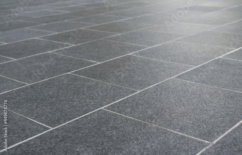 Dark gray granite tiles floor pattern texture perspective view background.