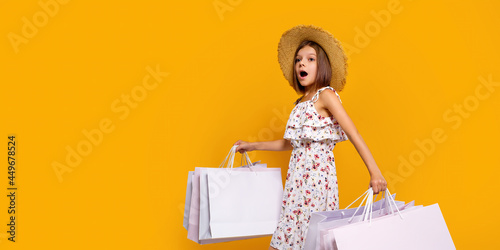 Portrait Of Joyful Teen Girl In Straw Hat With Bright Shopping Bags Over Yellow Background, Copy Space