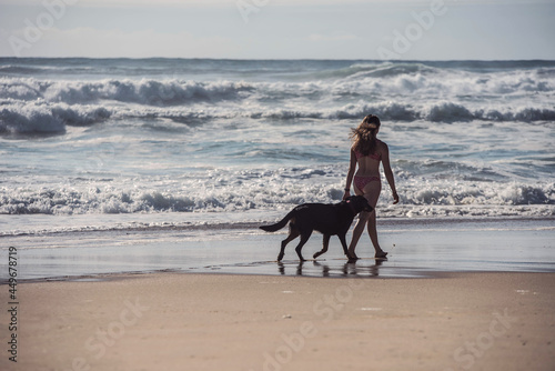 pretty young woman walking with her dog on the beach