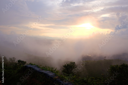 Destination and paradise of golden sunrise and sunset shining to the mist and fog in the jungle on the valley mountain. Aerial view of Rainy season in the tropical rainforest in Thailand.