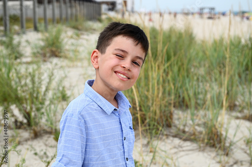 Headshot of adorable kid cute smiling standing against the backdrop of steppe thickets and sandy soil. Handsome child cute smiles looking at the camera.