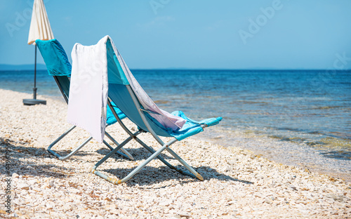 Empty armchair with towel on the sea beach.