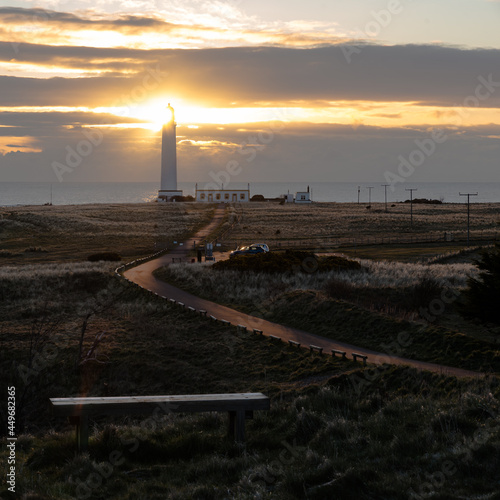 the rising sun illuminates the lantern of the lighthouse