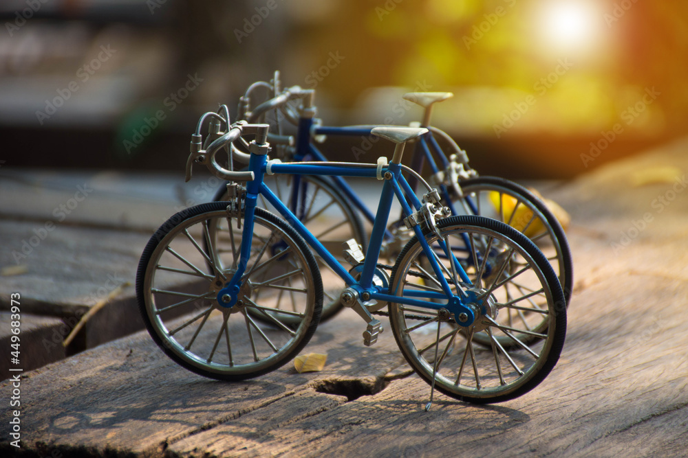 selected focus on vintage classic bike or bicycle model or toys standing on wooden table with blur bokeh background.