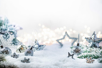 Christmas silver decorations on snow with fir tree branches and christmas lights. Winter Decoration Background