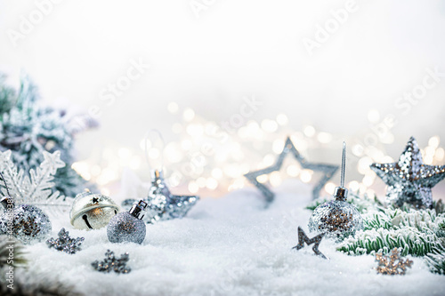 Fototapeta Christmas silver decorations on snow with fir tree branches and christmas lights
