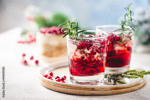 Refreshing drink with cranberries and rosemary on white background