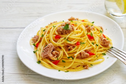  Healthy and easy Italian Traditional Dish"Spaghetti with tuna",spaghetti with tuna in olive oil,parsley,garlics,salt and peppers on plate with white wood table background.Copy space