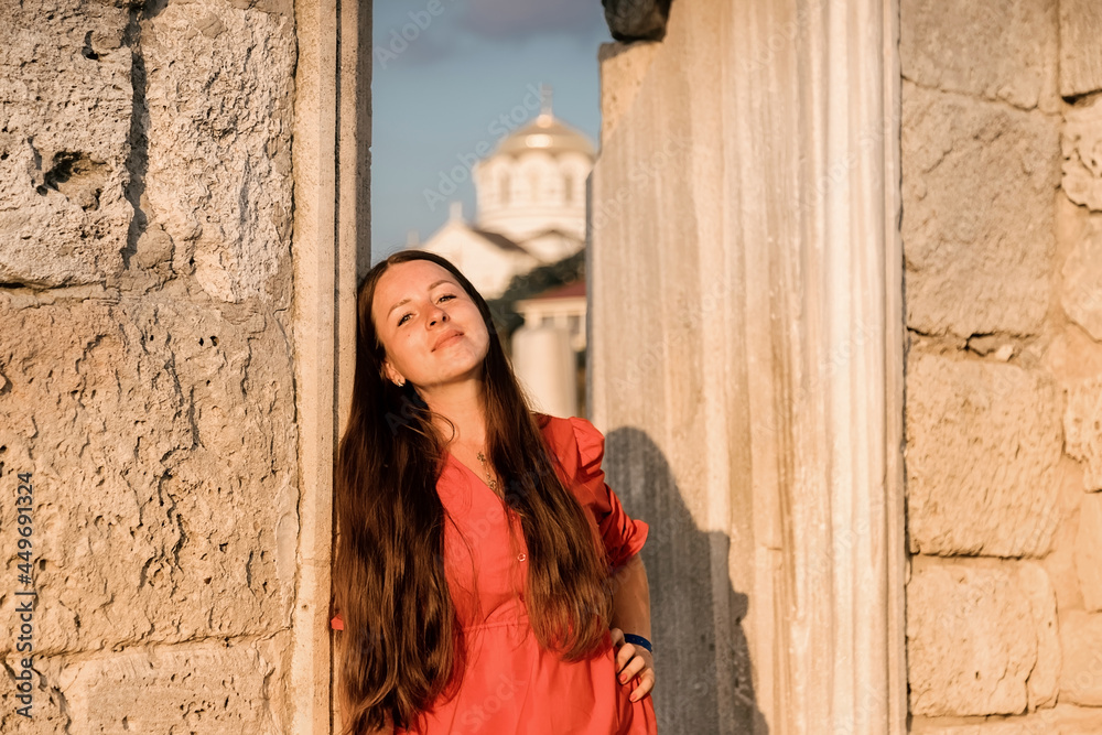 A girl in a red dress among the ruins of an ancient city, on the Crimean peninsula