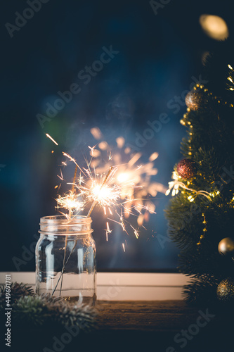 Photography Christmas or New Year party sparkler in a jar in front of the window on dark background