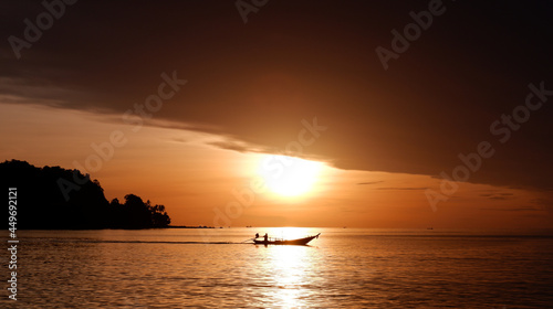 fishing boat in the ocean at sunrise, the sun shines through the boat