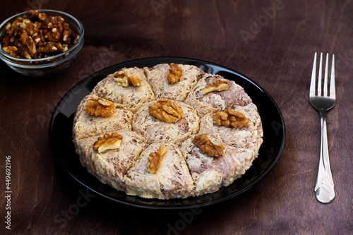 sunflower halva with fork and Turkish tea in traditional glass on the wooden table close-up. glass cup of black tea with walnuts on the dark brown background with copy space. Turkish desserts.