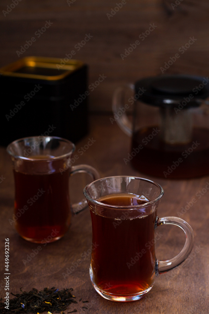 Turkish tea in traditional glass on the wooden table close-up. two glass cups of black tea with teapot on the dark brown background with copy space. vertical