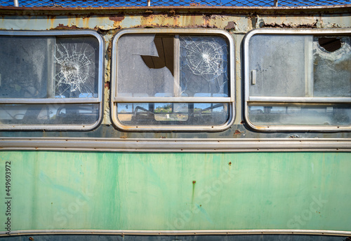 Abandoned old bus close up, side view. Vintage pattern with peeled paint and broken glass 