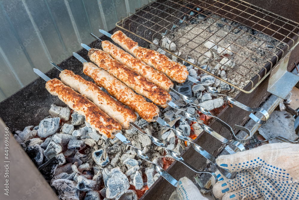 A man roasts a kebab on the coals in the grill. Outdoor picnic.