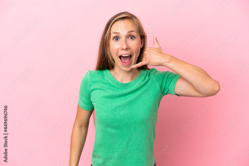 Young English woman isolated on pink background making phone gesture. Call me back sign Young English woman isolated on pink background making phone gesture. Call me back sign