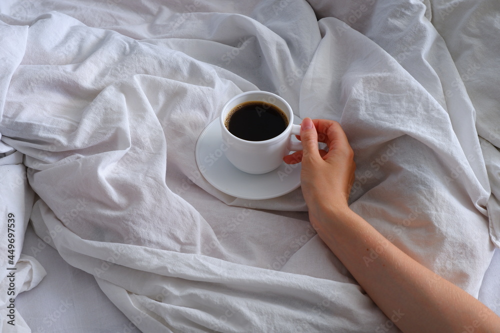 Girl holding a cup of coffee in bed. Breakfast in bed. Interior. Cosiness. Girl holding a cup of coffee in bed. Breakfast in bed. Interior. Cosiness.