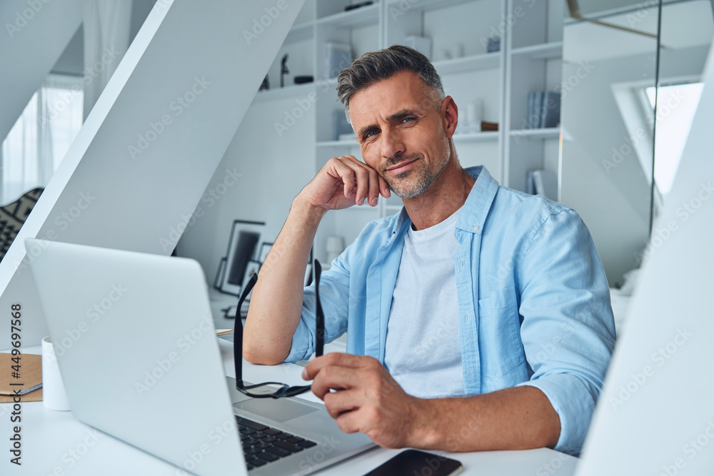 Confident mature man looking at camera while sitting at the office desk