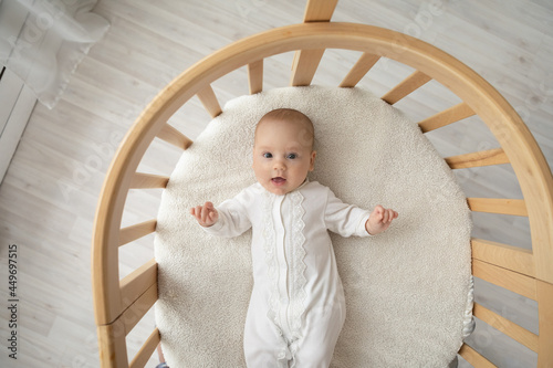 Billede på lærred Top view portrait of cute little Caucasian baby infant kid child lying in children bassinet at home