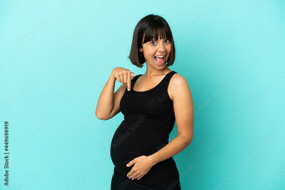 Woman over isolated background pregnant and pointing to the belly Woman over isolated background pregnant and pointing to the belly