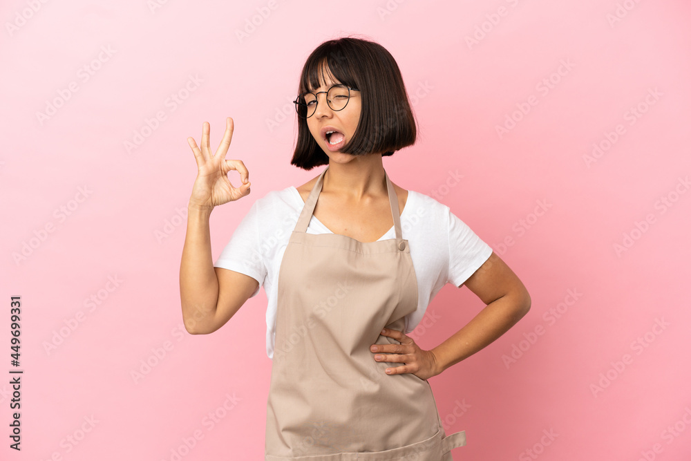 Restaurant waiter over isolated pink background showing ok sign with fingers Restaurant waiter over isolated pink background showing ok sign with fingers