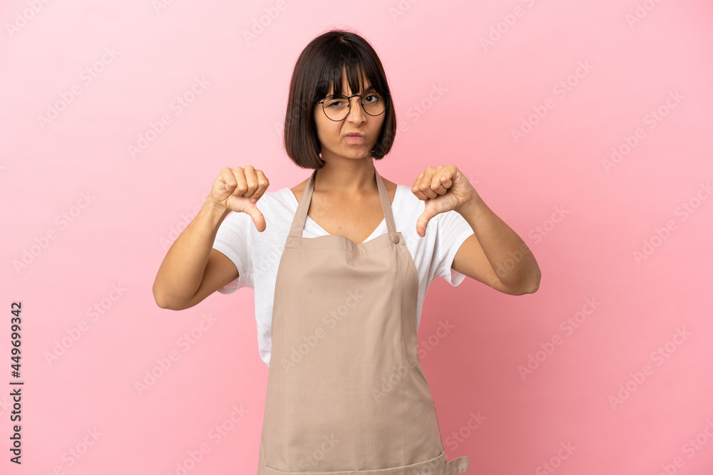 Restaurant waiter over isolated pink background showing thumb down with two hands Restaurant waiter over isolated pink background showing thumb down with two hands