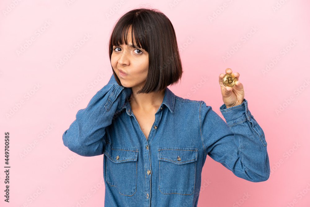 Young mixed race woman holding a Bitcoin isolated background having doubts Young mixed race woman holding a Bitcoin isolated background having doubts