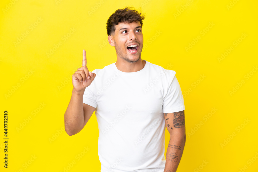 Young caucasian handsome man isolated on yellow background intending to realizes the solution while lifting a finger up Young caucasian handsome man isolated on yellow background intending to realizes the solution while lifting a finger up