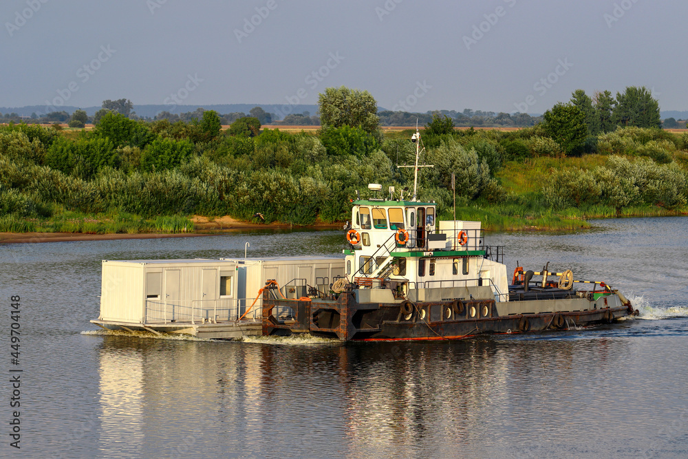 In the evening, a river tug with cargo goes along the Neman In the evening, a river tug with cargo goes along the Neman