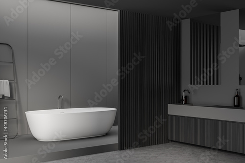 Corner of dark grey bathroom space with wood details and white tub